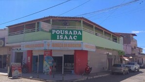 Un edificio de dos plantas con fachada verde y roja, que muestra un letrero que dice "POUSADA ISAAC".