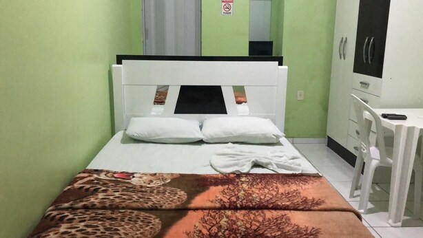Un dormitorio pequeño y ordenado con cama, escritorio y armario.