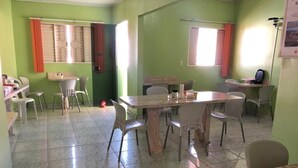 Un comedor con una mesa grande y sillas, una ventana con cortinas y piso de baldosas.