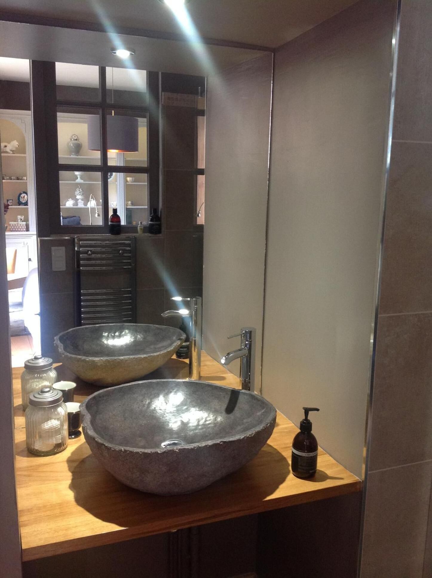 Ein modernes Badezimmer mit einem großen, runden Waschbecken aus Stein und einem Spiegel.