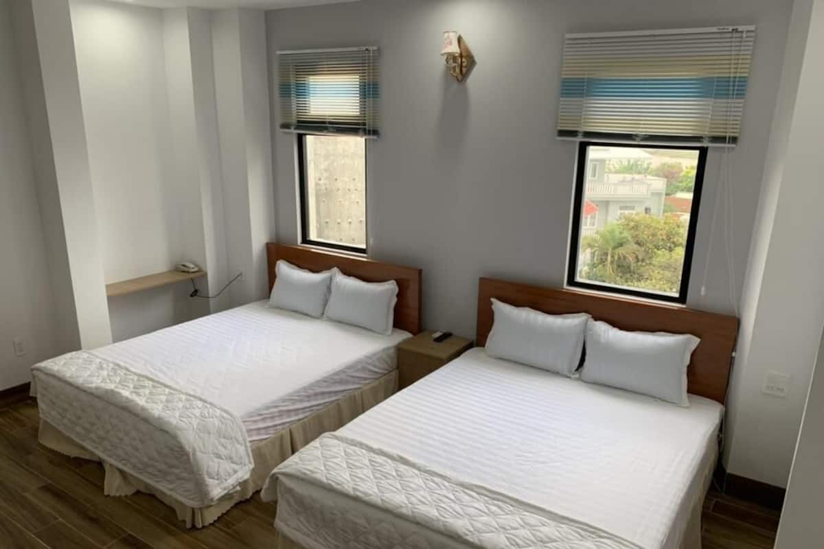 Two single beds with wooden headboards, white bedding, and a small bedside table with a lamp.