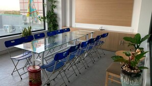 Una sala de reuniones moderna con una mesa de cristal, sillas azules, un armario de madera y plantas en macetas.