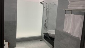 Un baño moderno con cabina de ducha de vidrio, un lavamanos blanco y un perchero con toallas dobladas.