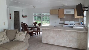 A compact kitchen with a dining area, a sofa, and a fireplace. - PARADISE CREEK COTTAGES ON THE BEACH. (Andros Town)