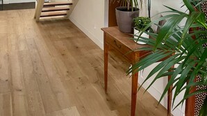 Eine moderne Treppe mit Holzboden und Glasgeländern, die zu einer Empore mit einem gerahmten Bild eines Kirchturms führt.