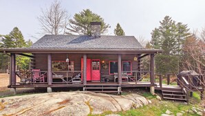 A log cabin with a porch, a red door, and a chimney. - 40 Acre Forested Privacy w/ Deeded Beach Access Near Acadia Schoodic (Prospect Harbor)