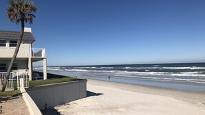 Una propiedad frente a la playa con balcón con vistas al océano, una palmera y una playa de arena.
