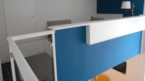 A room with a blue accent wall, a white desk, and a small window with a white lamp. - Manuela Apartments Piazza San Domenico in the historic center (Napoli)