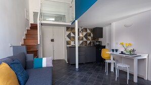 A modern apartment with a living area, kitchen, and a staircase leading to an upper floor. - Manuela Apartments Piazza San Domenico in the historic center (Napoli)