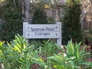 Une enseigne indiquant l’emplacement des « Sparrow Pond Cottages », entourée de verdure.