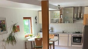 A modern kitchen with white cabinets, a refrigerator, and a dining area with a table and chairs. - Cozy apartment in a rural idyll (Marienhagen)