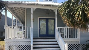 A two-story house with a porch, a blue door, and a white railing. - Barrier Dunes Cottage  Steps from beach/pool/tennis. 2/2 plus loft - SPECIALS!!! (Port St Joe)