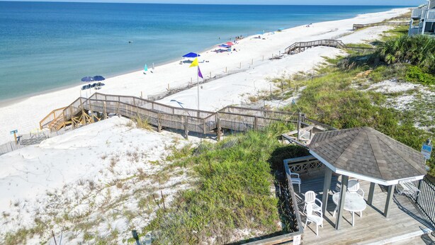 A beach with a wooden boardwalk leading to a gazebo with outdoor seating. - Barrier Dunes Cottage  Steps from beach/pool/tennis. 2/2 plus loft - SPECIALS!!! (Port St Joe)
