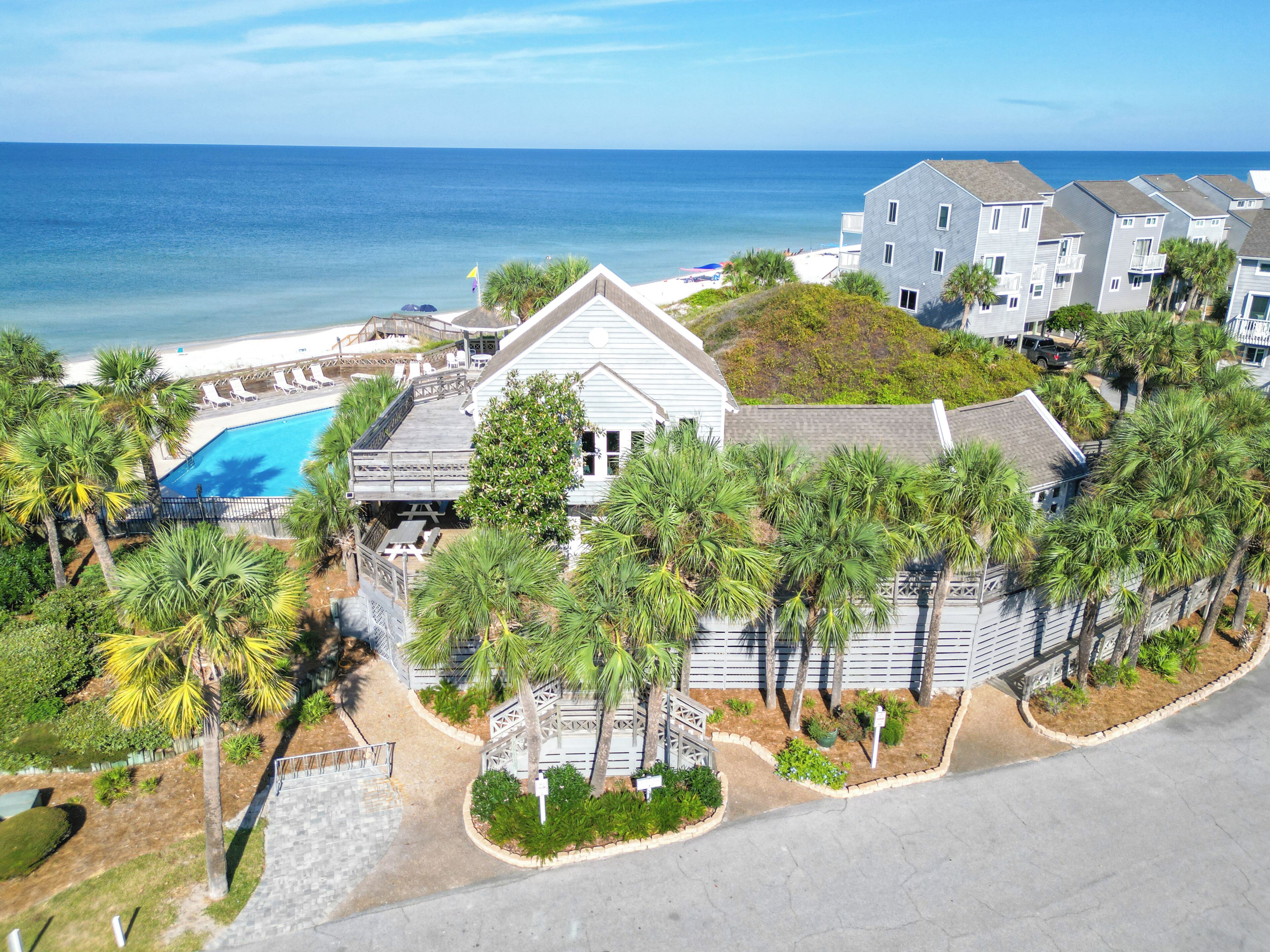 A coastal residential area with a swimming pool, multiple-story buildings, and a view of the ocean.