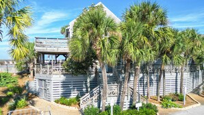 A building with a white exterior, a balcony, and palm trees. - Barrier Dunes Cottage  Steps from beach/pool/tennis. 2/2 plus loft - SPECIALS!!! (Port St Joe)