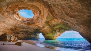 A natural rock formation with a cave-like opening, a sandy beach, and a view of the sea. - Magnificent architect-designed villa in traditional Algarve style (Carvoeiro)