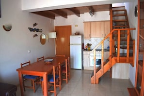 A kitchen with wooden cabinets, a white refrigerator, and a wooden staircase.
