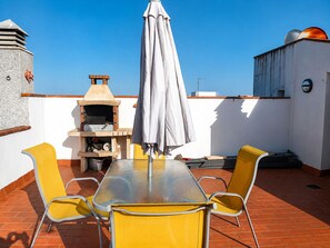 A rooftop terrace with a table, chairs, a grill, and a large umbrella. - 238-Apartment with terrace and view on canal (Empuriabrava)