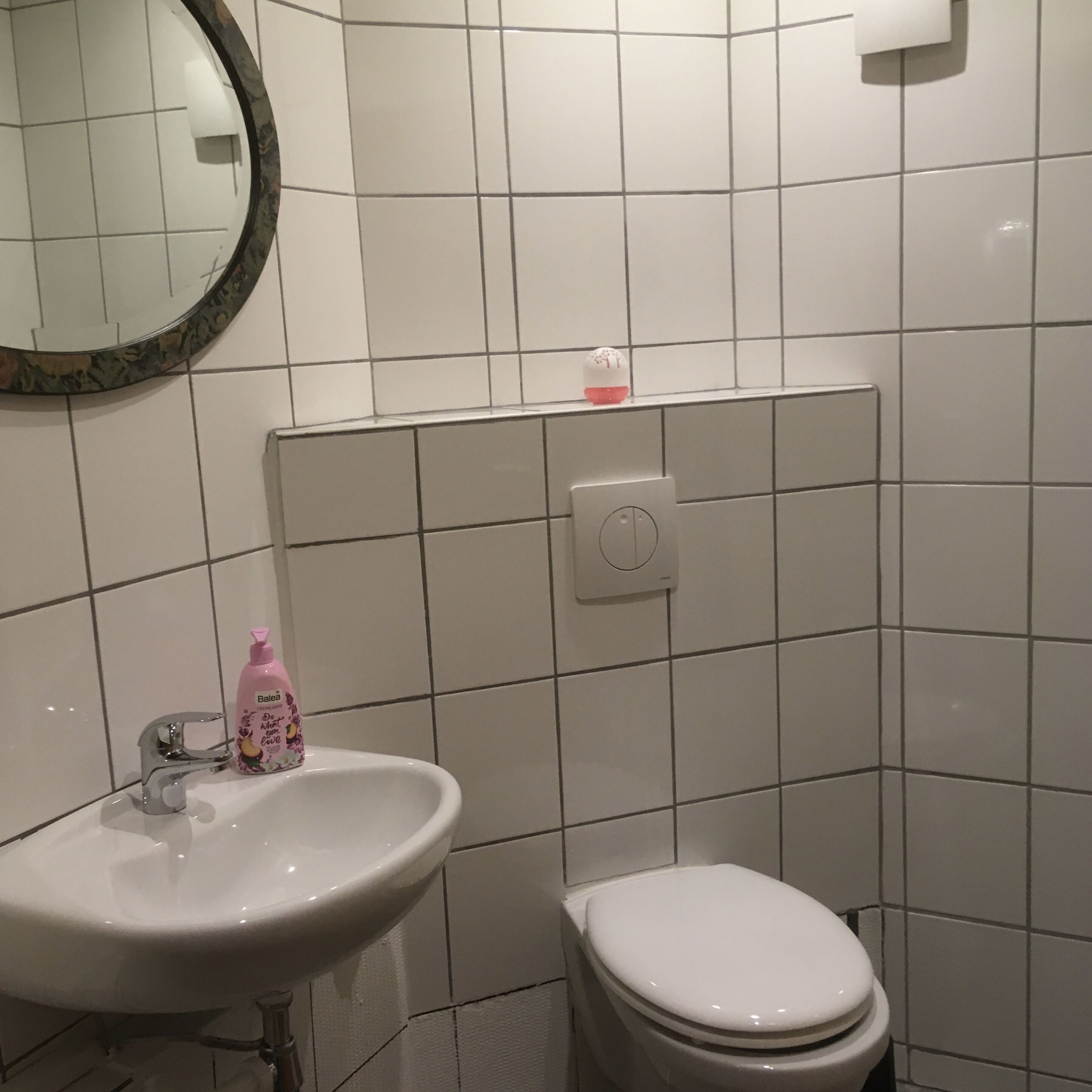Une salle de bain avec un lavabo, des toilettes et un miroir.