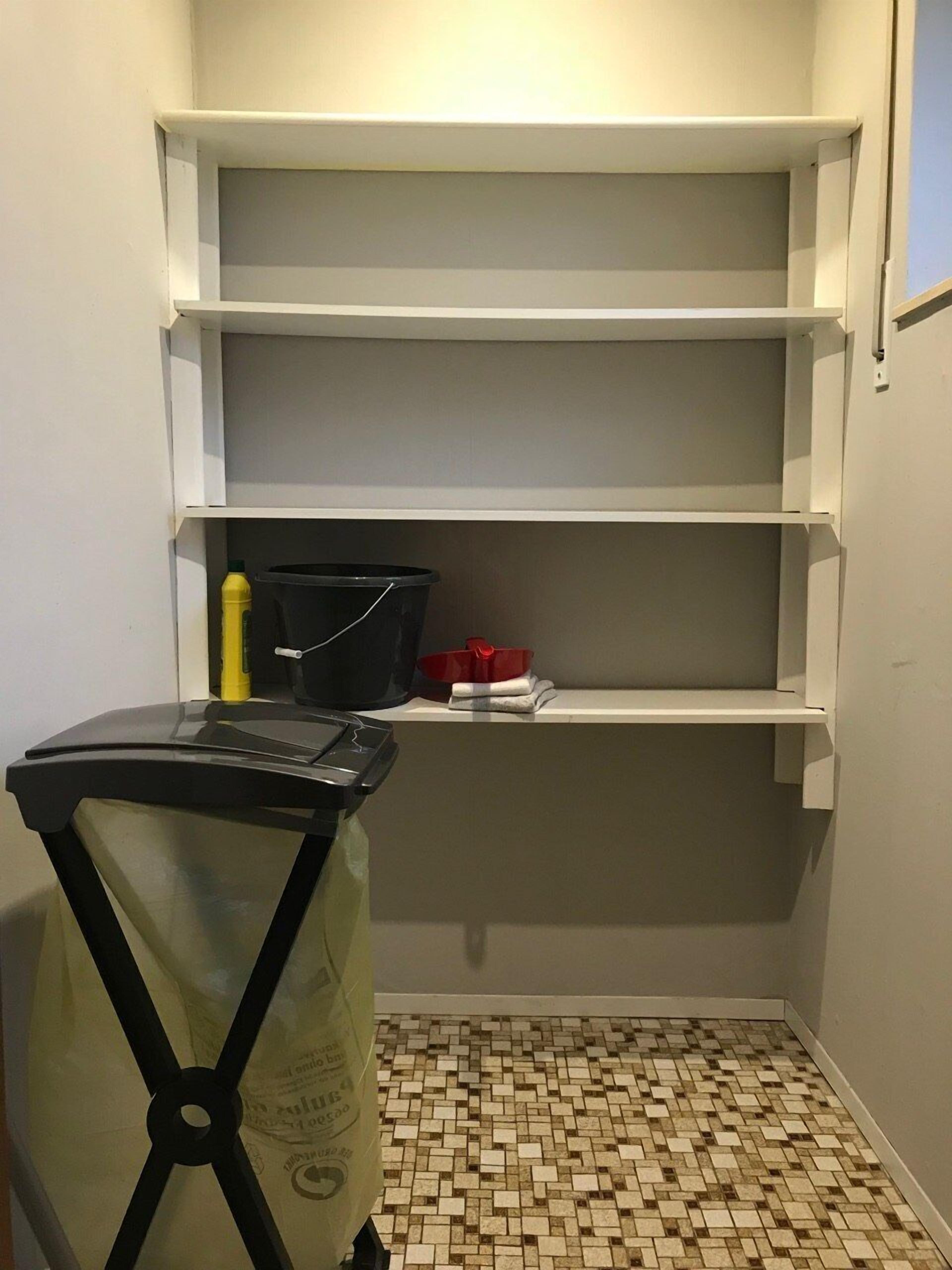 Un petit espace de rangement fermé, doté de trois étagères et d’un sol carrelé.