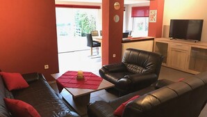 Un salon comprenant un canapé, deux fauteuils, une table basse et un téléviseur.