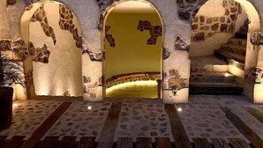 Ein Zimmer mit Steinwand, Holzboden und einem Bett mit gelber Kopfteil.