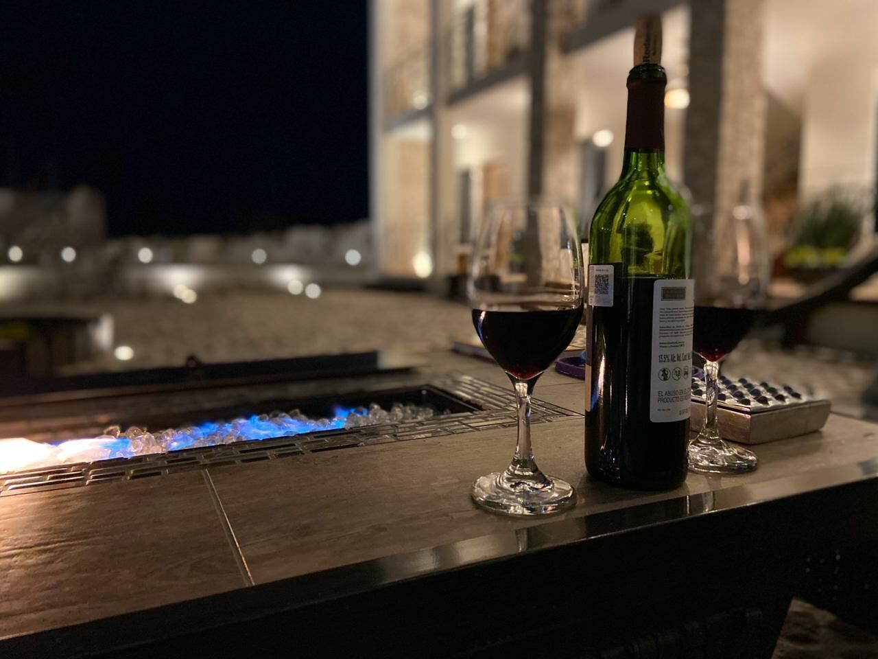 A bar area with a bottle of wine and two glasses on a counter.