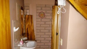 A narrow bathroom with a wooden door, a white sink, and a mirror.
