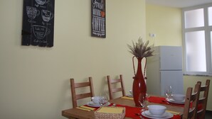 A dining area with a table set for four, a vase with dried flowers, and wall decorations including a coffee-themed sign.
