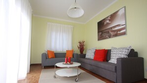 A living room with two grey sofas, a white coffee table, and a painting on the wall.
