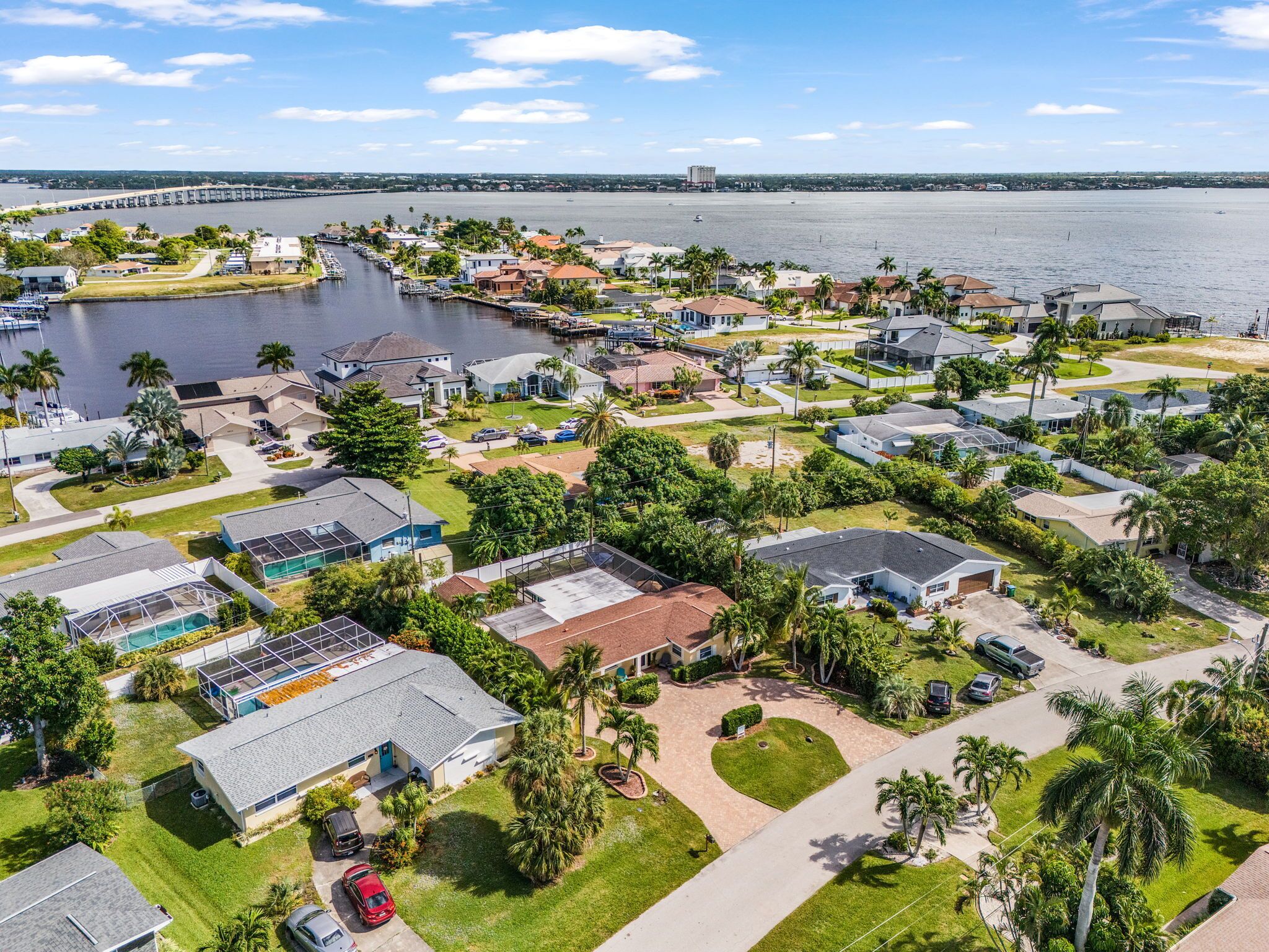An aerial view of a residential area with houses, a marina, and a bridge in the background.