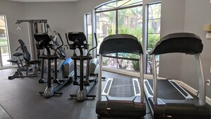 Un gimnasio con cintas de correr, elípticas y equipo de pesas.
