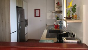 A compact kitchen with a refrigerator, sink, and a small countertop. - Caribbean Village, holiday apartment, Guadeloupe, 97180 (Sainte-Anne)