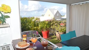 A balcony with a table set for breakfast, including toast, beverages, and a plant. - Caribbean Village, holiday apartment, Guadeloupe, 97180 (Sainte-Anne)