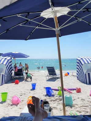 A beach scene with umbrellas, beach chairs, and people in the water.