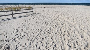 Una playa arenosa con huellas y una valla de madera.