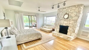 Un dormitorio espacioso con una cama grande, una chimenea de piedra y vistas al exterior.
