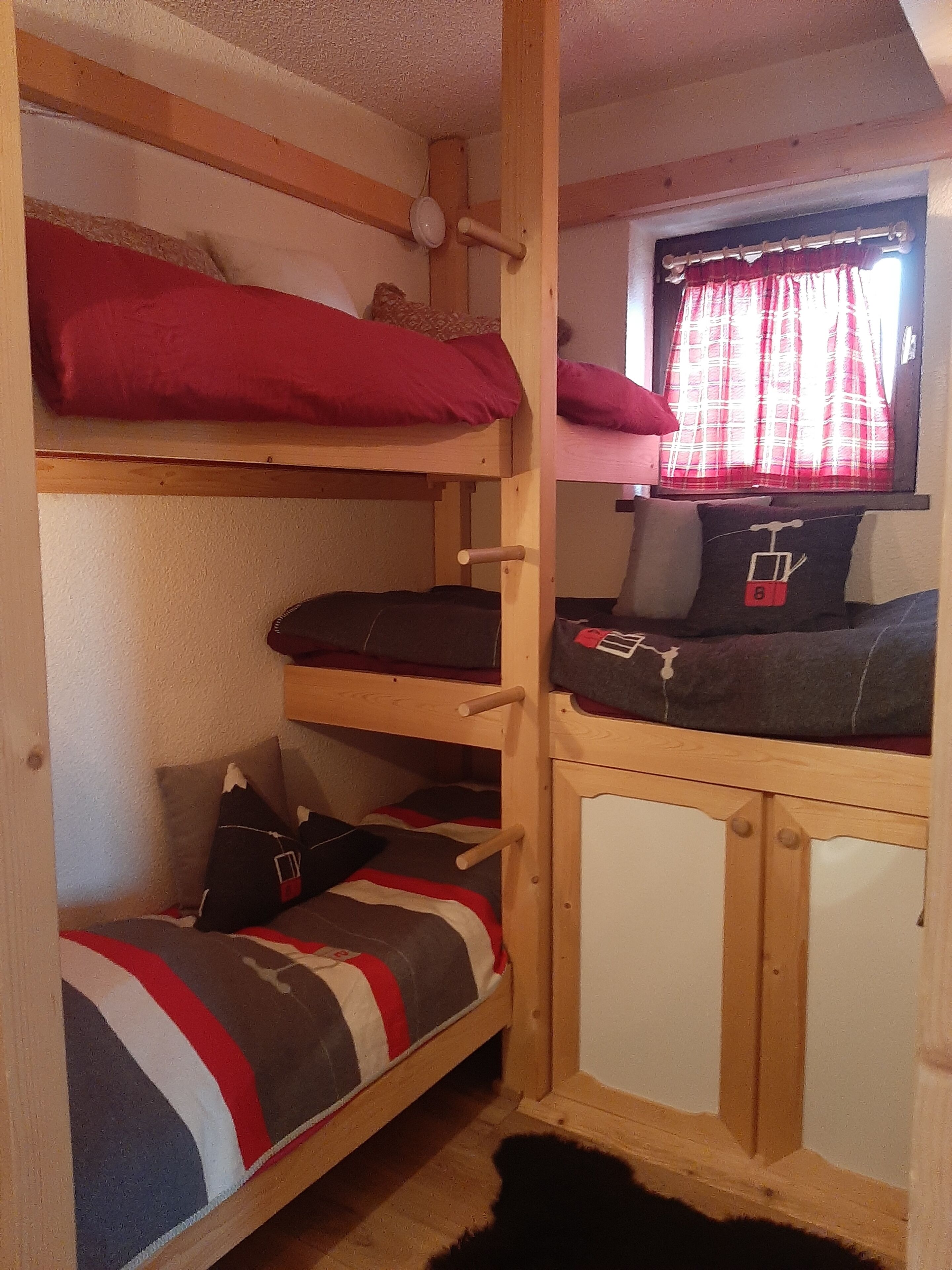 A bunk bed room with a window and a small desk.