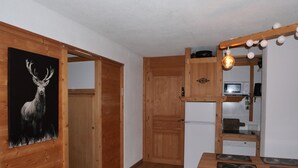 Un interior de madera con una zona de cocina, que incluye un refrigerador, un microondas y una mesa de comedor con sillas.