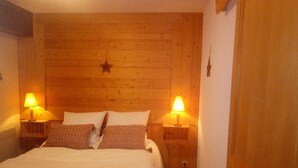 Un dormitorio acogedor con cabecera de madera, dos lámparas de noche, una cama con almohadas estampadas y una decoración con forma de estrella en la pared.