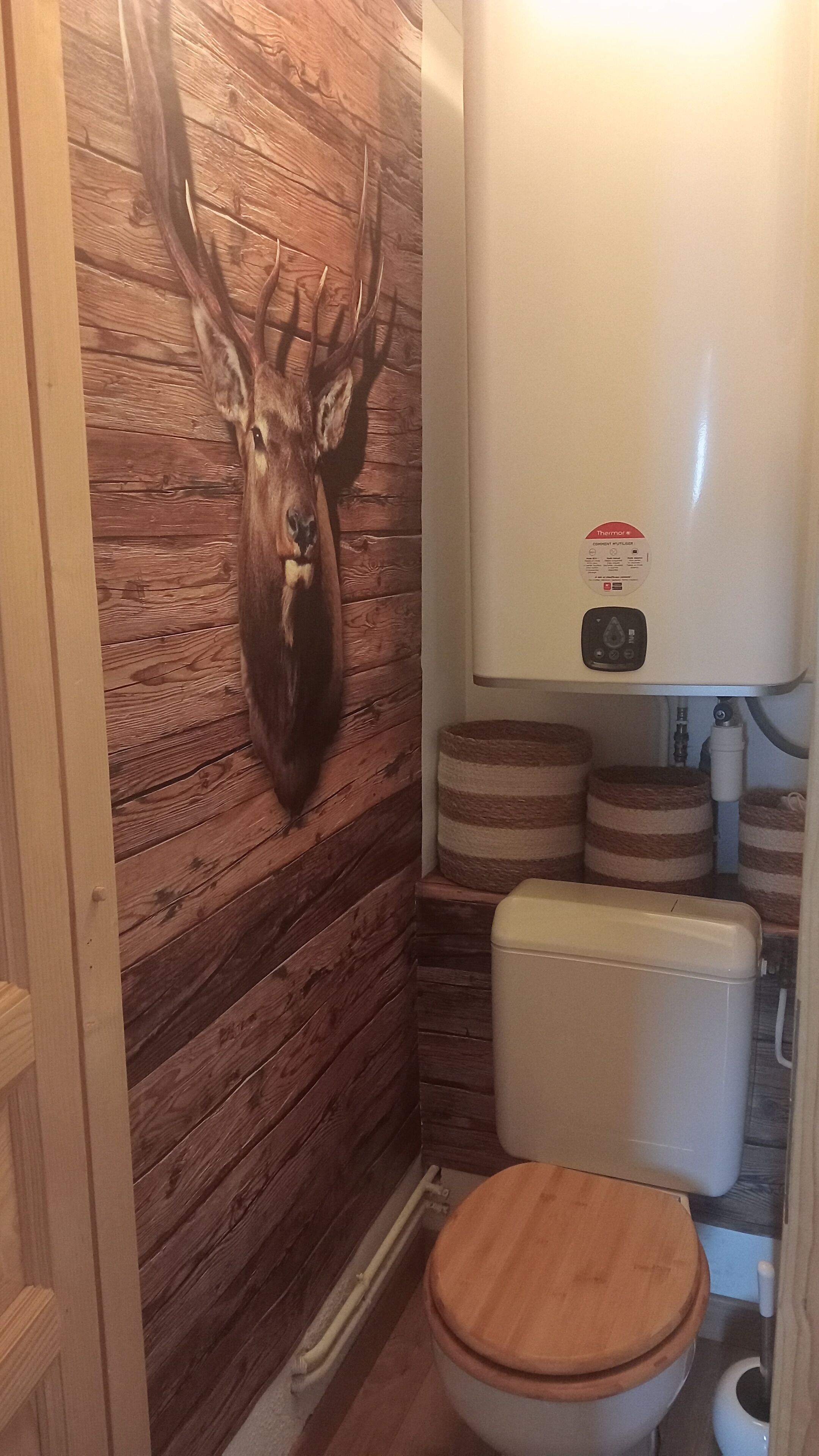 A bathroom with wooden walls, a wooden toilet seat, and a white toilet.