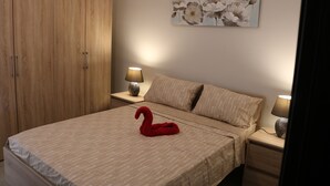 Ein Schlafzimmer mit einem Bett, einem Holzschrank, zwei Nachttischen mit Lampen und einem Wandbild mit Blumenmuster.