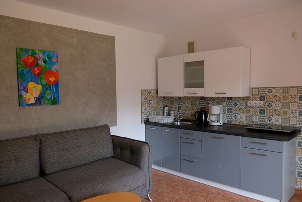 A compact kitchen with grey cabinets, a coffee maker, and a tiled backsplash. - 3 room apartment with terrace, 450m from the sandy beach, close to the nature park, garden (Rowy)