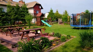 A backyard with picnic tables, a slide, and a trampoline. - 3 room apartment with terrace, 450m from the sandy beach, close to the nature park, garden (Rowy)