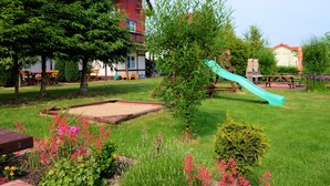 A playground with a slide, surrounded by green grass and trees. - 3 room apartment with terrace, 450m from the sandy beach, close to the nature park, garden (Rowy)