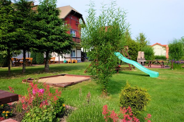 A playground with a slide, surrounded by green grass and trees. - 3 room apartment with terrace, 450m from the sandy beach, close to the nature park, garden (Rowy)
