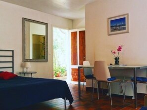 Une pièce comprenant un lit, un bureau, une chaise, un miroir et une fenêtre.
