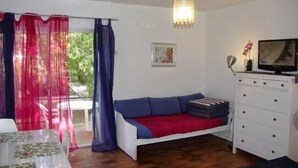 A room with a bed, a white dresser, a television, and a window with curtains. - Studio & large garden 200m Calvi beach (Calvi)