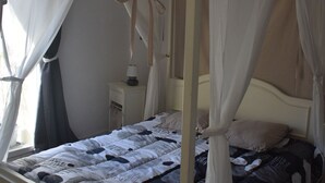 A four-poster canopy bed with a white and black patterned bedspread, a bedside table with a lamp, and a window with curtains. - DUPLEX OF 110 M2 NEAR QUAY AND SHOPS, 8 persons (Port-Vendres)
