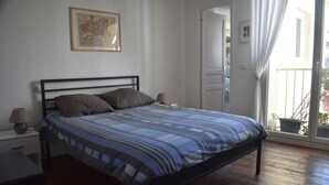 A bedroom with a bed, a nightstand, a lamp, and a window with curtains. - DUPLEX OF 110 M2 NEAR QUAY AND SHOPS, 8 persons (Port-Vendres)